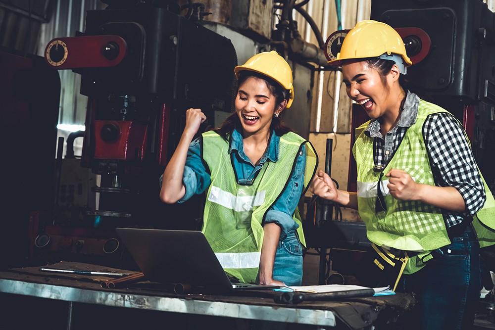 Two factory job worker celebrate success together in the manufacturing workshop