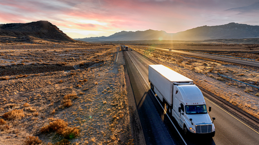 White Semi-Trailer Truck Heading down a four-lane Highway at Dusk delivering a load in the southeastern Utah desert on interstate 70 east bound