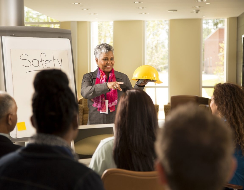 Business woman gives safety presentation at office. Multi-ethnic group of professionals.